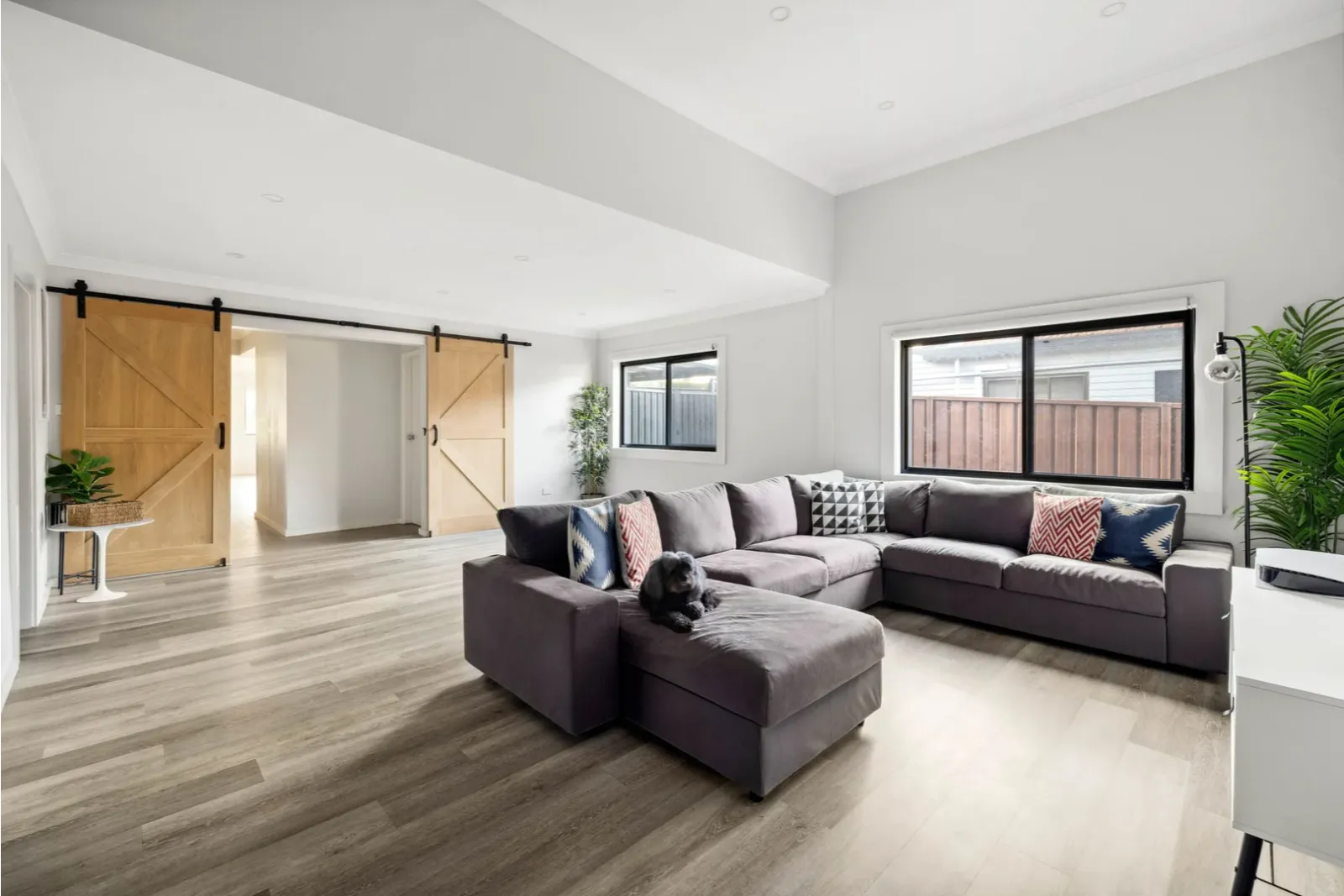 Open-plan living area renovation featuring timber-look flooring, barn-style sliding doors, and modern interior finishes.