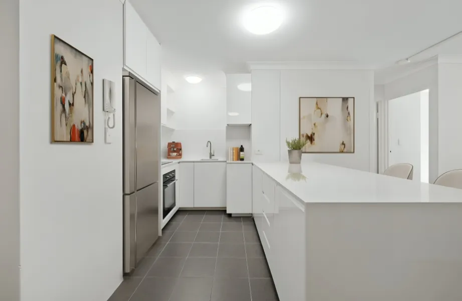 Modern kitchen renovation featuring white cabinetry, stone benchtops, and a spacious breakfast bar.